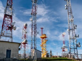 A group of tall telecom towers with dish and panel antennas that use cavity filters to control frequencies and reduce interference.